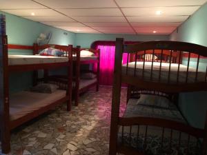 波托韦洛Hostal Portobelo的一间设有几张双层床和粉红色照明的房间