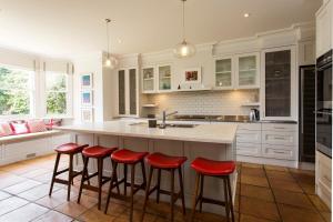 悉尼Victorian Masterpiece的厨房配有白色橱柜和红色吧台凳