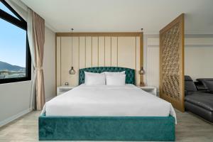 岘港Lupin Center Hotel Danang的卧室配有一张白色的大床和一张沙发。
