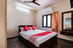 拉加蒙德里OYO Seera Enclave的一间卧室配有一张带红色枕头的床和一扇窗户