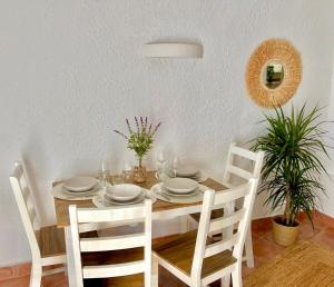卡拉莫若尔Beachfront Apartment in Cala Morell的餐桌,配有白色的盘子和椅子