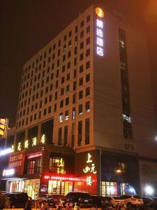 无锡JTOUR Inn Wuxi Railway Station Shangmadun Metro Station的一座高大的建筑,晚上有标志