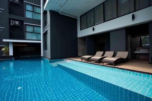 曼谷Iconic Hotel的一座带躺椅的游泳池位于大楼旁