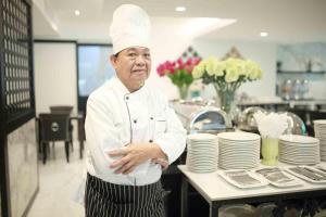 曼谷Iconic Hotel的站在厨房里的厨师,手臂交叉