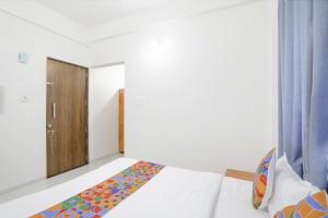 纳西克FabHotel Blue Ocean MNJ Resort的一间卧室配有一张床和一扇木门