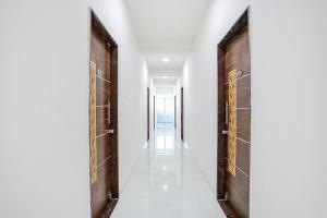纳西克FabHotel Blue Ocean MNJ Resort的走廊设有两扇木门,走廊设有白色墙壁