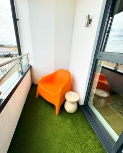 拉姆斯盖特Stunning Beach Front Apartment with Sea views, FREE Parking & Balcony的窗户房间里的一个橙色长凳