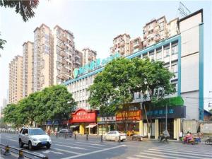 成都City Comfort Inn Chengdu Jinniu Wanda Liangjiaxiang Metro Station的一条城市街道,有汽车在街道上行驶,街道上拥有高大的建筑