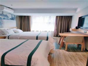 长春City Comfort Inn Changchun Wenhua Square Xi Zhonghua Road的酒店客房设有两张床、一张桌子和一台电视。