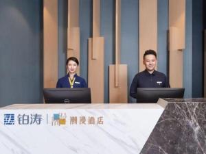 深圳ZMAX Hotels Shenzhen Lianhuacun Metro Station的两人坐在桌子上,手提电脑