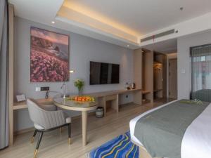 昆明Gya Hotel Kunming Zijin Center Xiaodongcun Metro Station的一间卧室配有一张床、一张桌子和一台电视。