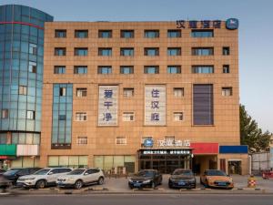 济南Hanting Hotel Jinan Guo Branch的前面有汽车停放的建筑