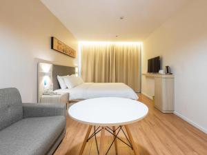 济南Hanting Hotel Jinan Guo Branch的酒店客房配有床、沙发和桌子。