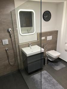 巴特乌拉赫TOP Ferienwohnung的一间带水槽、卫生间和时钟的浴室