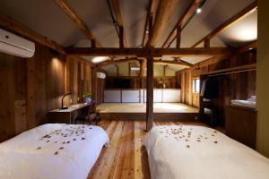 丰冈市ゲストハウス長閑的配有木墙和木地板的客房中的两张床