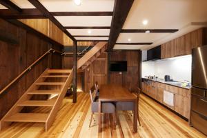 丰冈市ゲストハウス長閑的厨房以及带木桌和楼梯的用餐室。