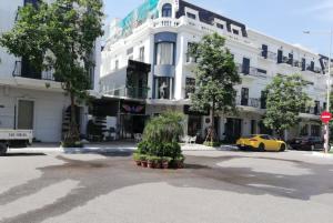 下龙湾Hạ Long Legend Hotel的一座白色的建筑,前面有一个黄色的汽车