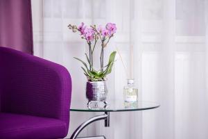 柏林尼古拉公寓酒店的花瓶和紫色椅子的玻璃桌