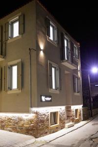 希俄斯Vasilicari Apartments的街上的一座建筑,晚上有窗户