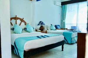 班布里普拉萨海滩酒店的一间卧室配有两张带蓝白色床单的床