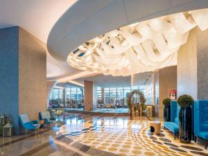 迪拜迪拜市区索菲特酒店的大堂设有蓝色椅子和大吊灯。