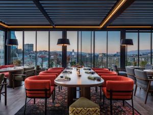 第比利斯Swissôtel Tbilisi的餐厅设有桌椅和大窗户。