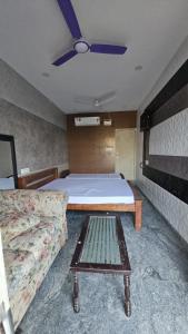 钦奈MR.WHITE PRIME RESIDENCY的一间卧室配有一张床、一张沙发和吊扇。