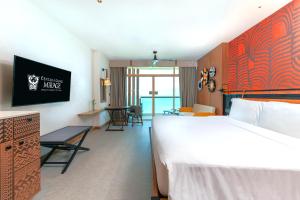 北芭堤雅Centara Grand Mirage Beach Resort Pattaya的酒店客房设有一张大床和一张桌子。