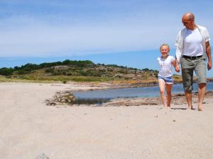 阿灵厄4 person holiday home in Allinge的海滩上散步的男人和女人