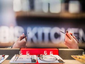 伊西莱穆利诺依西雷莫里诺塞纳河谷宜必思酒店的两个人坐在桌子上,手放在筷子上