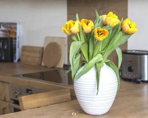 奥茨塞巴德·迪尔哈根OSTSEEPANORAMA Penth Nr 29 max 4 P的白色的花瓶,上面有黄色的花朵