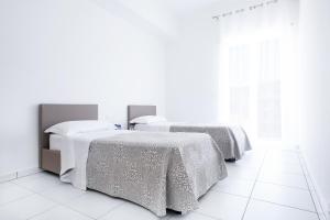 卡普多兰多维勒公寓式酒店的白色客房的两张床,铺有白色地板
