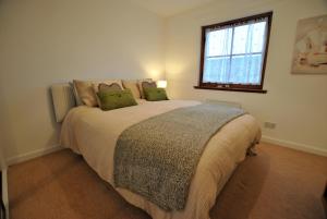 克雷尔Meadowshores Apartment Crail的一间卧室配有一张带绿色枕头的大床