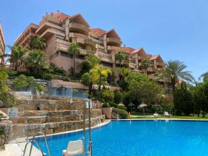 马贝拉Magna Lujoso apartamento en Marbella的一座带游泳池的度假村,位于一座建筑前