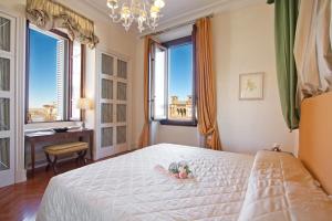 佛罗伦萨赛里斯托里宫殿酒店的一间卧室配有床、两个窗户和一张书桌