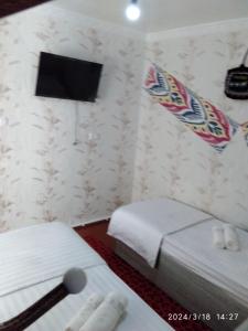 布哈拉Nur-Niso Guest House的一间酒店客房,设有两张床和电视