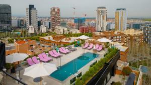 马德里Hotel Pinar Plaza的享有带椅子和遮阳伞的游泳池的上方景致