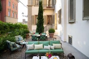 佛罗伦萨赛里斯托里宫殿酒店的庭院设有绿色的沙发和桌椅