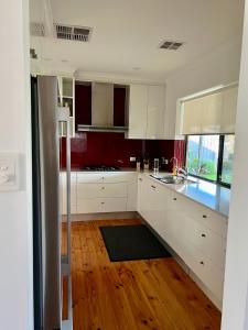 Henley Beach SouthParkview Cottage的厨房铺有木地板,配有白色橱柜。