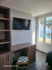 尼斯蓝色浪花酒店的一间设有一张桌子的房间,墙上配有电视