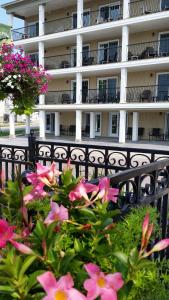 金卡丁海港旅馆的建筑前方有粉红色花的黑色围栏