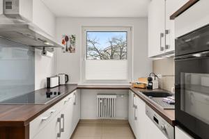 沃尔夫斯堡FREE LIVING - Jungle Design Apartments, Zentrum, Parkplatz, Küche, Wlan的厨房配有白色橱柜和窗户。