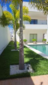 贝贝里比Casa de praia em Beberibe的一座拥有两棵棕榈树的游泳池和一座建筑