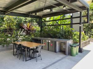 布里斯班Modern Homely 2BR APT w Parking Bowen Hills的庭院设有木桌、椅子和植物