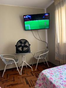 皮斯科Habitación doble的一间设有两把椅子和一张桌子的房间,墙上设有一台电视机