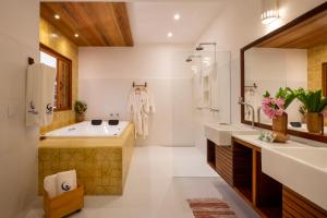 托兰克索望夏四乐章宾馆的浴室配有2个盥洗盆、浴缸和大镜子
