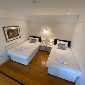 汤顿Farmers Arms的配有白色墙壁和木地板的客房内的两张床