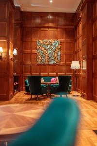 亚琛Parkhotel Quellenhof Aachen的一间带椅子和桌子的房间以及挂毯