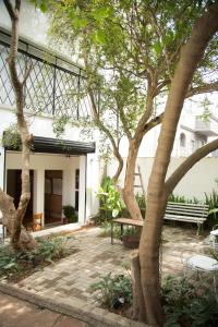 圣保罗Guest Urban Hotel Design Pinheiros的一座建筑前方带长凳和树木的庭院