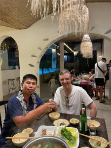潘切Red Sands Pool Villa的两个男人坐在桌子上吃着饭
